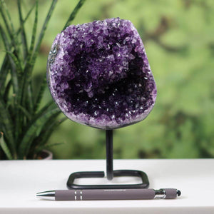 Dark purple Amethyst Druse from Uruguay on metal stand beside pen for scale, showcasing intense natural crystal formation.