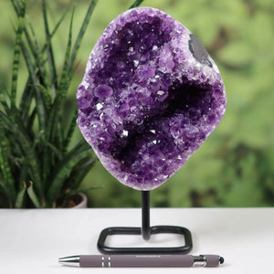 Dark purple Uruguay amethyst druse geode on metal stand, vivid crystal formation, desk decor with a pen for scale