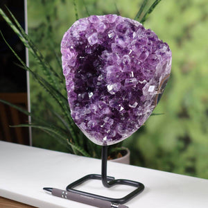 Deep purple Uruguay Amethyst geode on metal stand displayed on table, enhancing home decor with natural crystal formations.