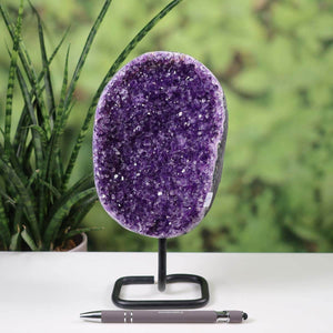 Dark purple Uruguay Amethyst drusen geode displayed on a metal stand with a pen for scale, enhancing home decor.