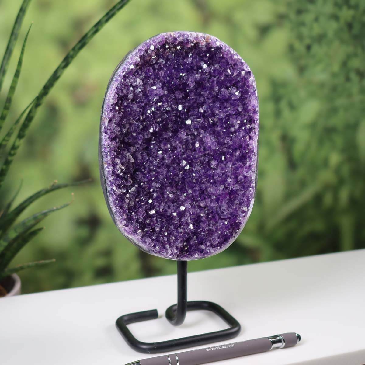 Dark purple Uruguay Amethyst drusen geode displayed on a metal stand with a pen for scale, enhancing home decor.