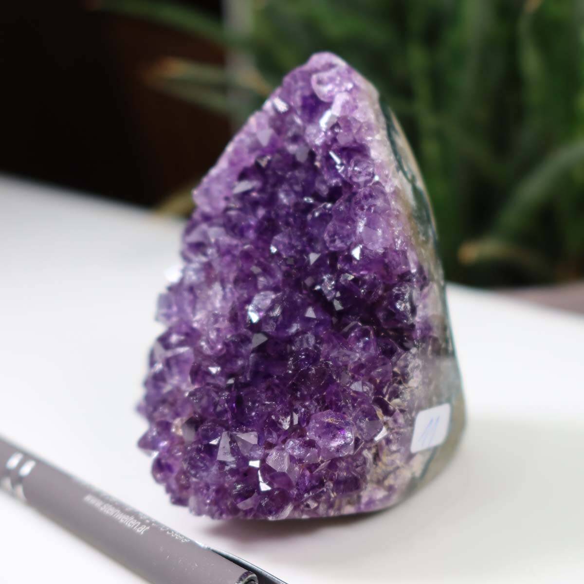 Intense purple Uruguay Amethyst mini geode displayed with a pen for scale, showcasing regular crystal growth and deep violet color.