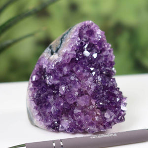 Intense purple Uruguay Amethyst mini geode displayed with a pen for scale, showcasing regular crystal growth and deep violet color.