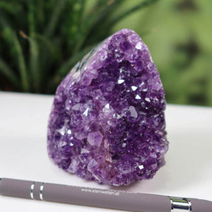 Deep purple Uruguay Amethyst mini geode displayed on a white surface, showcasing intense natural crystal formations.