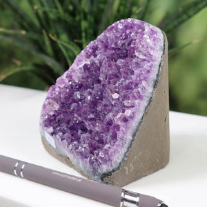 Dark purple Uruguay amethyst mini geode with intensely colored crystals displayed near a pen for scale.