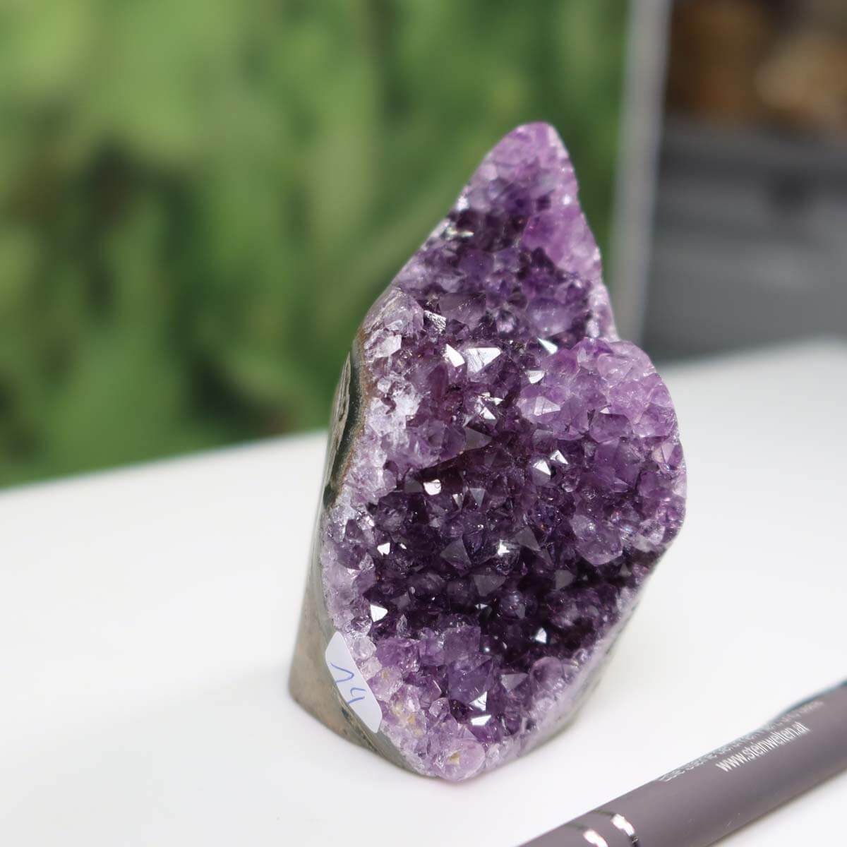 Uruguay Amethyst mini geode NR 14 with intense violet crystals on a white surface, pen for scale