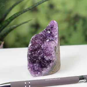 Uruguay Amethyst mini geode NR 14 with intense violet crystals on a white surface, pen for scale