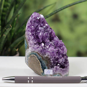 Uruguay Amethyst Mini Geode with intense purple crystals, unique piece number 16 displayed on a white surface with a pen for scale.