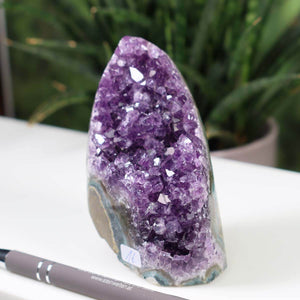 Deep purple Uruguay Amethyst Mini Geode displayed on a table, showcasing intense violet crystals and natural shine, with pen for scale.