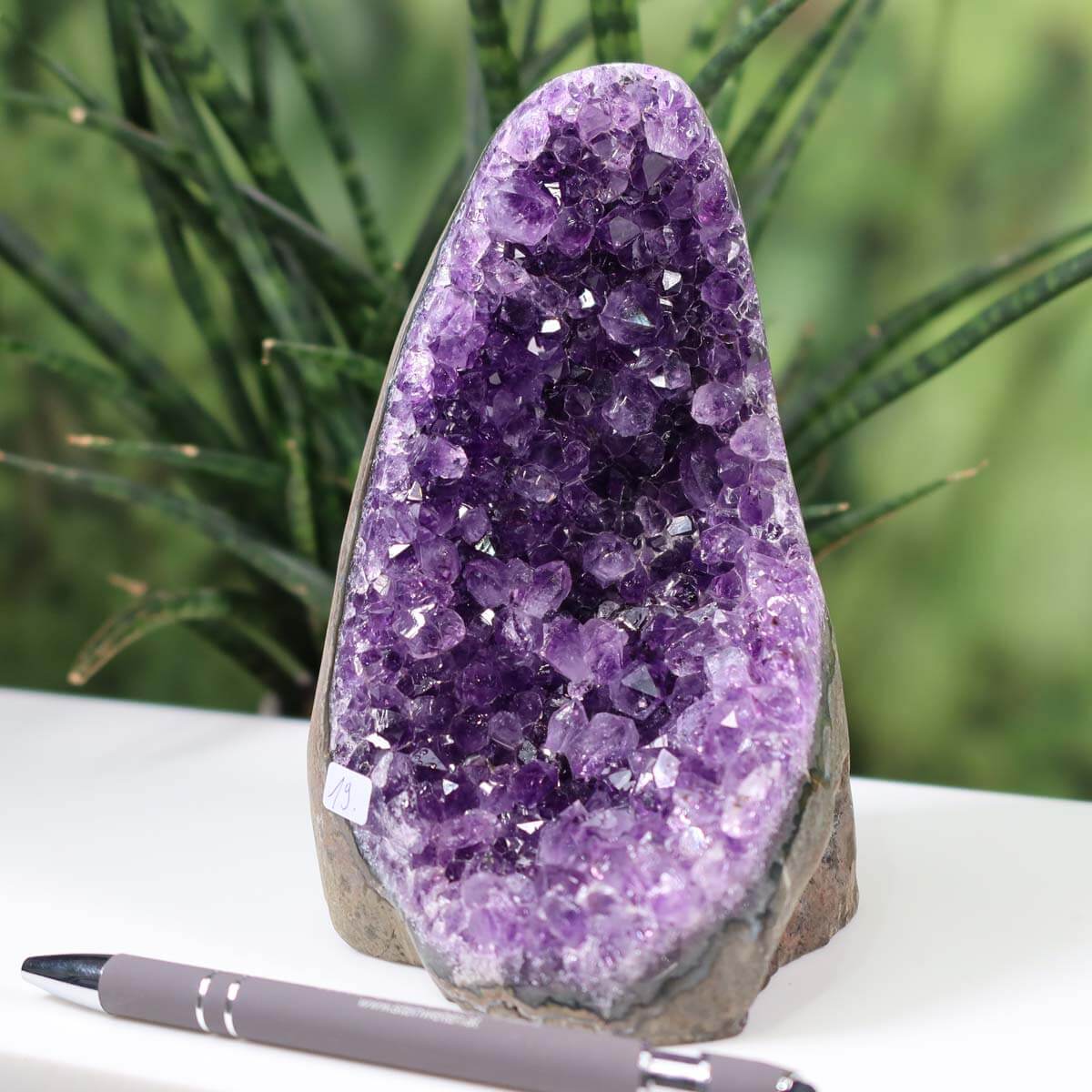 Intense purple Uruguay Amethyst mini geode with natural crystal formation, displayed outdoors with a pen for scale, unique piece number 19.