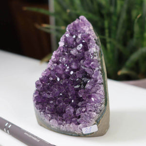 Uruguay Amethyst Mini Geode showing deep violet crystals, labeled as unique piece number 21, displayed on a white surface.