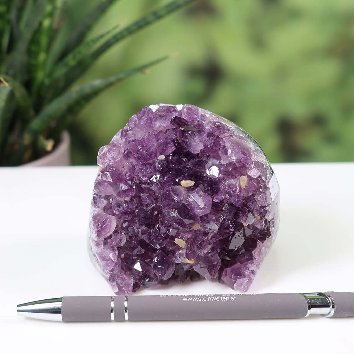 Uruguay Amethyst mini Geode NR-2 with deep purple crystals displayed on a white surface, showcasing its intense sparkle and regular crystal formation.