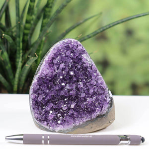 Intense purple Uruguay amethyst mini geode with natural crystal formation showcased beside a pen for scale