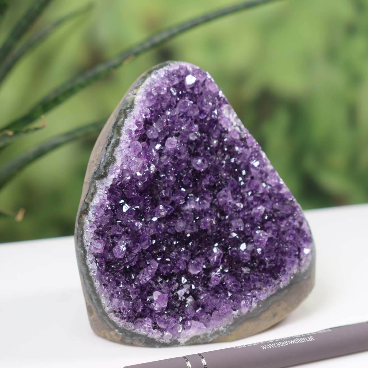 Intense purple Uruguay amethyst mini geode with natural crystal formation showcased beside a pen for scale