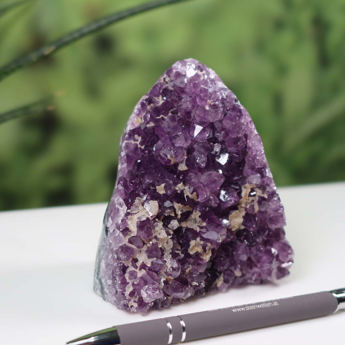 Intensely colored Uruguay Amethyst mini geode displayed alongside a pen for scale, showcasing dark purple crystals.