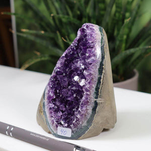 Uruguay Amethyst mini geode number 40 with intensely dark purple crystals on display, labeled clearly, beside a pen for scale.