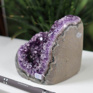 Uruguay Amethyst Mini Geode, Unikat NR 42, with intense dark purple crystals displayed on a table, enhancing natural beauty.