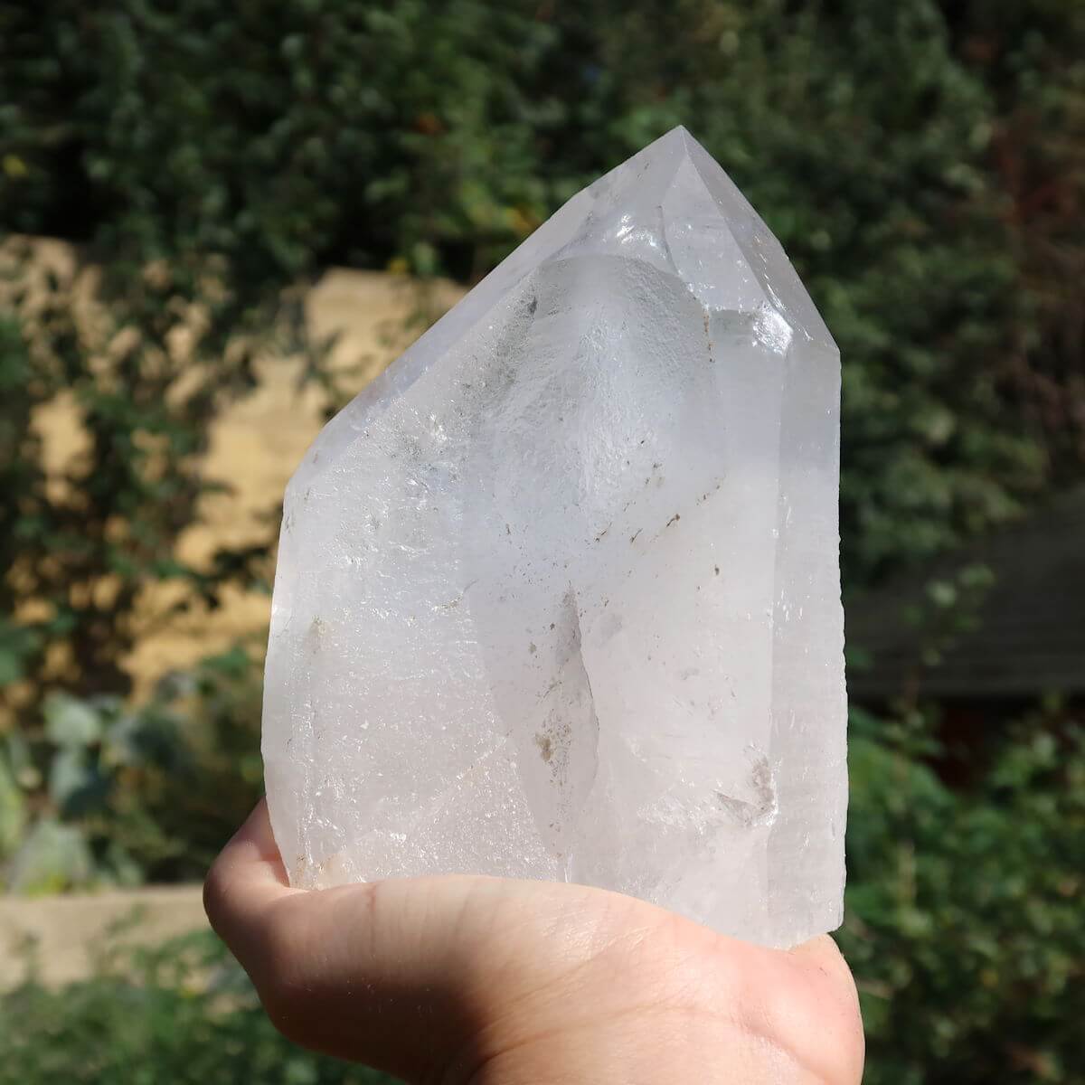 Hand holding polished Bergkristall quartz crystal with faceted surfaces, ideal for clarity and meditation, from Brazil