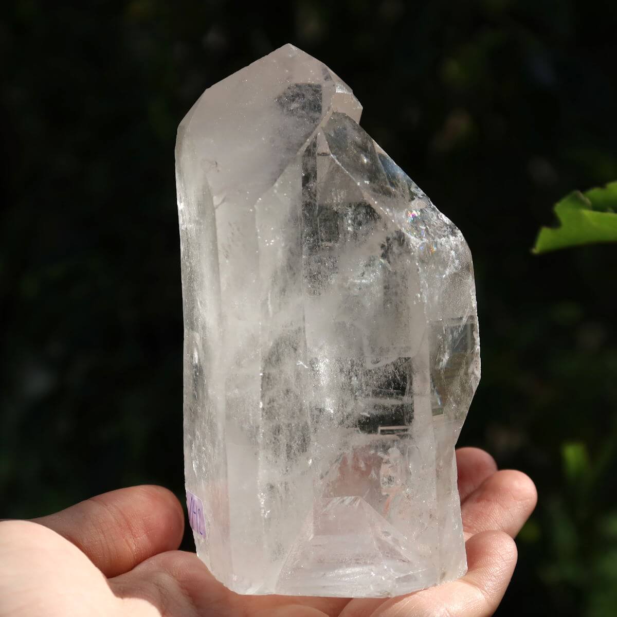 Hand holding a polished quartz crystal point from Brazil, ideal for clarity and meditation, displaying natural sparkle and faceted sides.