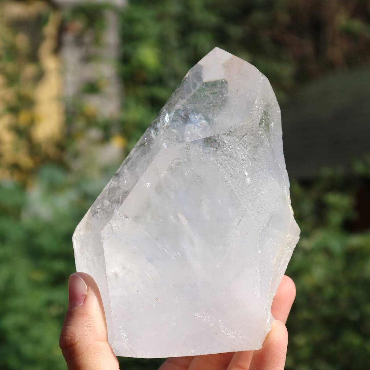 Hand holding a unique, cut quartz crystal point measuring 12x6 cm, ideal for clarity and meditation, sourced from Brazil.