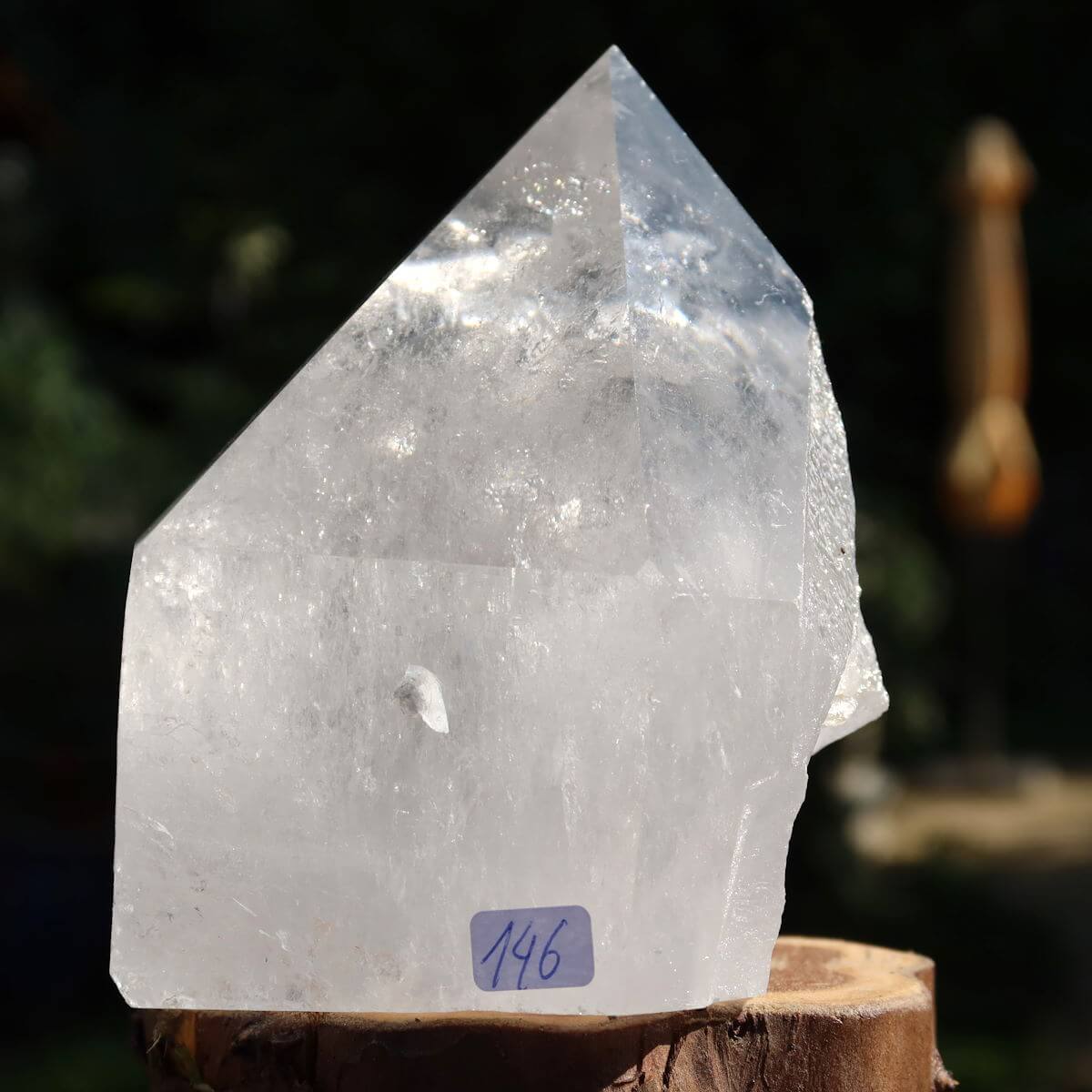 Close-up of a Brazilian quartz crystal point with a polished finish on a wooden base, labeled 146, ideal for clarity and meditation.