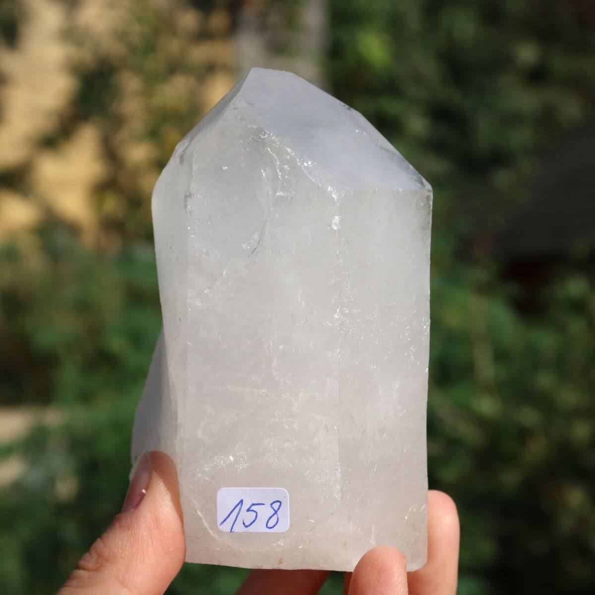 Clear quartz crystal point, Unikat Nr. 158, 9x6 cm size, for clarity and meditation, hand-held against a blurred background.