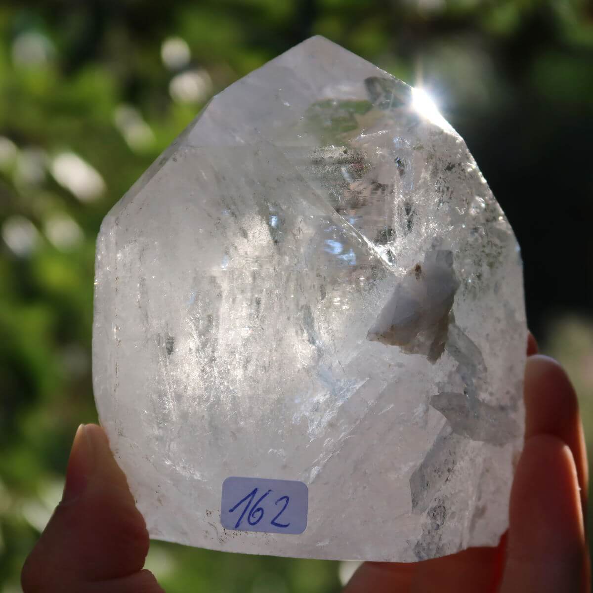 Person holding a unique Brazilian quartz crystal point, Bergkristall Unikat Nr. 162, with polished facets for clarity and meditation.