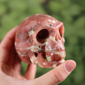 Handcrafted crystal skull made from natural stone with unique patterns, collector's item, 7x6 cm, held in hand.